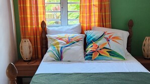 Een bed met houten frame, groene wanden en gordijnen.