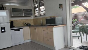 Een compacte keuken met een koelkast, magnetron en een klein spoelbakje.
