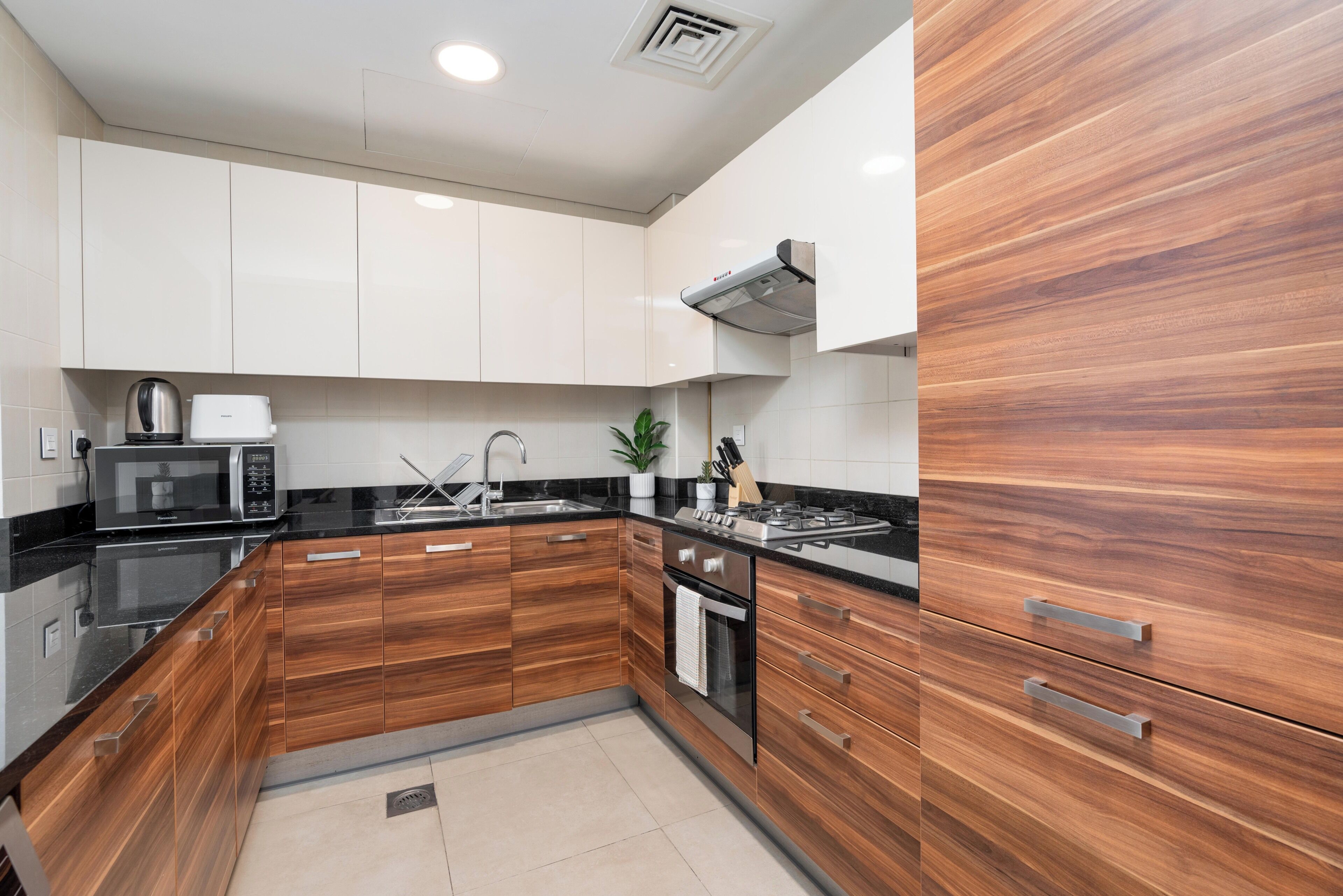 Una cocina moderna con armarios de madera, microondas, estufa y lavaplatos.