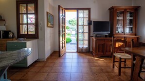 A kitchen with a dining area, a television, and a cabinet. - BeLocations - Villa 50 meters from the sea (Solanas)