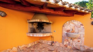 A stone-tiled patio with a stone oven and a stone sink. - BeLocations - Villa 50 meters from the sea (Solanas)