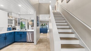 A modern kitchen with blue cabinets, a dishwasher, and a staircase leading to a living area. - Lakefront Villa with 6 Seat Golf Cart (Miramar Beach)
