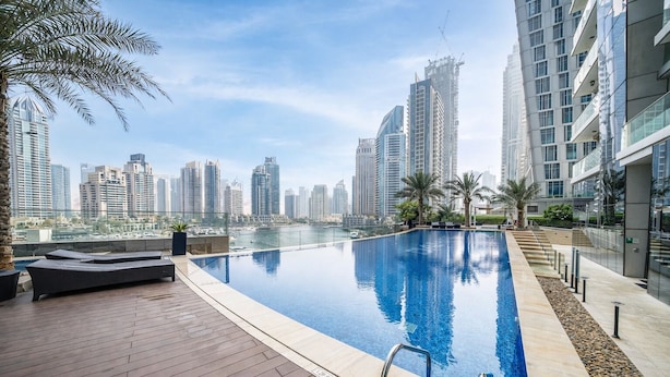 Ein moderner Poolbereich mit Blick auf die Stadt, einer Holzterrasse und Liegemöglichkeiten.