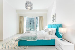 Ein Schlafzimmer mit einem Bett, einem Nachttisch, einer Lampe und einem Fenster mit Vorhängen.