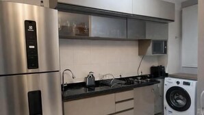 Una cocina moderna con electrodomésticos de acero inoxidable, microondas integrado y lavadora.