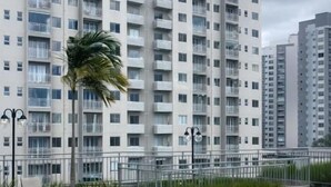 Un área de piscina en la azotea con una mesa redonda y sillas, rodeada por un edificio de gran altura con balcones.