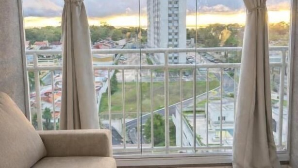 Una habitación con un amplio ventanal, un sofá y vistas a un paisaje urbano.