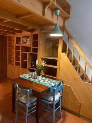 A wooden dining table with chairs, a potted plant, and a staircase with wooden railings. - Appartamento nel centro storico di Firenze (Florenz)