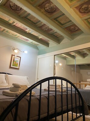 Ein Schlafzimmer mit einem Bett, einem Spiegel und einer Decke mit Zierleisten.