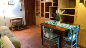 Un coin repas avec une table en bois, deux chaises, une plante en pot et un sol carrelé.