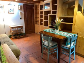 A dining area with a wooden table, two chairs, a potted plant, and a tiled floor. - Appartamento nel centro storico di Firenze (Florenz)