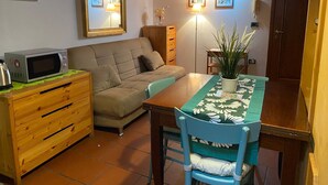 Un espace de vie compact comprenant un coin cuisine, un canapé, une table à manger et une chaise.