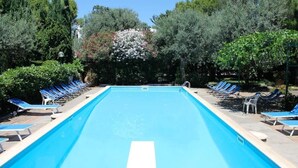 A rectangular swimming pool with a white center line, surrounded by blue lounge chairs and greenery. - Cactus Cottage With pool and a stone's throw from the famous Blue Grotto! (Anacapri)
