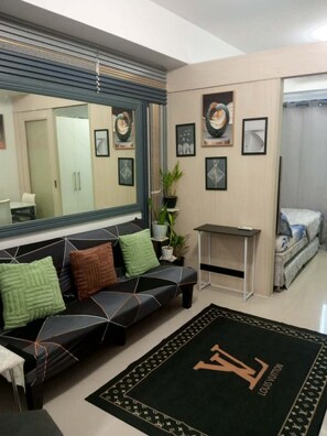 A modern living room with a sofa, a coffee table, a large mirror, and framed artwork on the walls. - Sea Residences Condominium Tower E/F Philippines-1015-Little peaceful hide away (Pasay City)