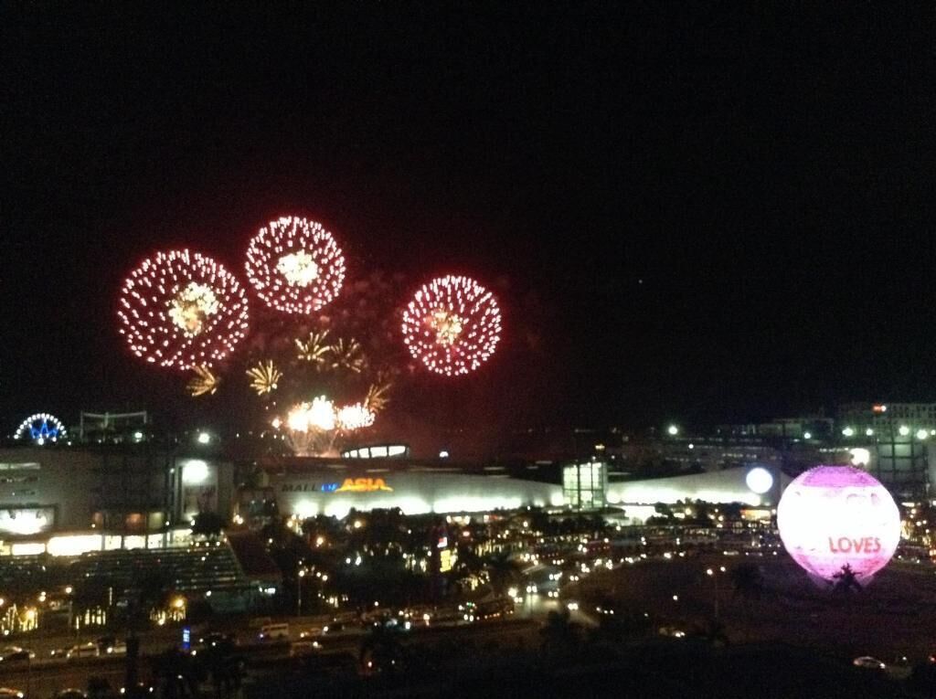 A nighttime view of a cityscape with fireworks in the sky and a large illuminated sphere with the word 'LOVES' on it.