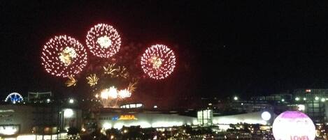 A nighttime view of a cityscape with fireworks in the sky and a large illuminated sphere with the word 'LOVES' on it.