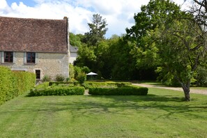 A stone building with a tiled roof, surrounded by a well-maintained garden with hedges and a lawn. - La Petite Cornière (Macé)