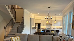 A living room with a sectional sofa, a coffee table, and a staircase. - Game Room Luxury Home @ Battery Chef Kitchen Deck (Marietta)