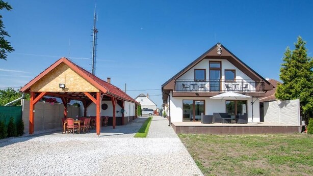 A two-story house with a covered patio and a balcony. - Room-pension -villa Vintage Room B 105 (Tomášikovo)
