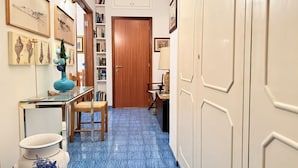A hallway with a blue-tiled floor, a wooden door, a bookshelf, and framed artwork on the walls. - S306 - Sirolo, two-bedroom apartment with parking space (Sirolo)