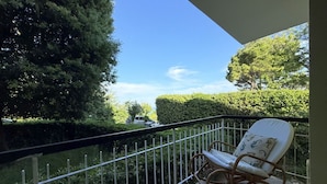 A balcony with a white rocking chair, a metal railing, and a view of a hedge and trees. - S306 - Sirolo, two-bedroom apartment with parking space (Sirolo)