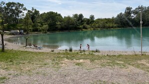 Ein See mit einem Kiesweg, Bäumen und einer Rasenfläche.