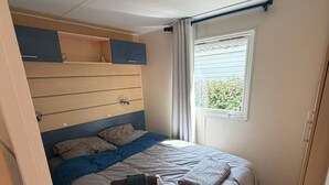 Ein Schlafzimmer mit Etagenbett, einem Fenster mit Vorhängen und Holzboden.