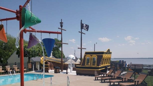 A swimming pool with water features, a pirate-themed building, and lounge chairs.