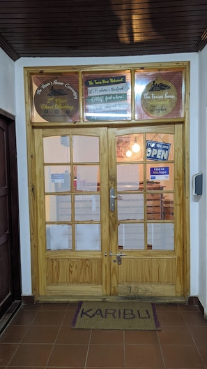 A wooden double door with glass panels, a sign indicating 'The Train's House Restaurant' and 'Open,' and a 'Visa' sign. - The Hub Train House Hakuna Matata (Zanzibar)