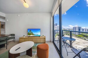Una sala de estar moderna con televisión, asientos y un balcón con vistas a la ciudad.