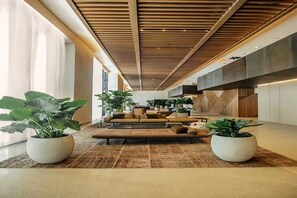 Ein modernes Interieur mit einer zentralen Sitzecke, Holzboden und Topfpflanzen.