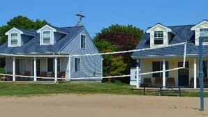 A beach house with a porch, a small attached structure, and a volleyball net. - Marina Haven 2BR Villa #14 at South Beach Resort — Private Beach, Pools, Marina (Lakeside Marblehead)