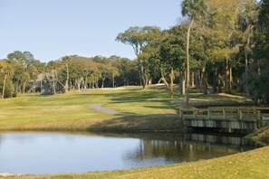 A golf course with a pond, a wooden bridge, and trees. - BLOCK CW Ocean Ridge 1br (Edisto Island)