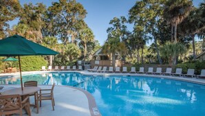A swimming pool with lounge chairs and a table, surrounded by trees. - BLOCK CW Ocean Ridge 1br (Edisto Island)