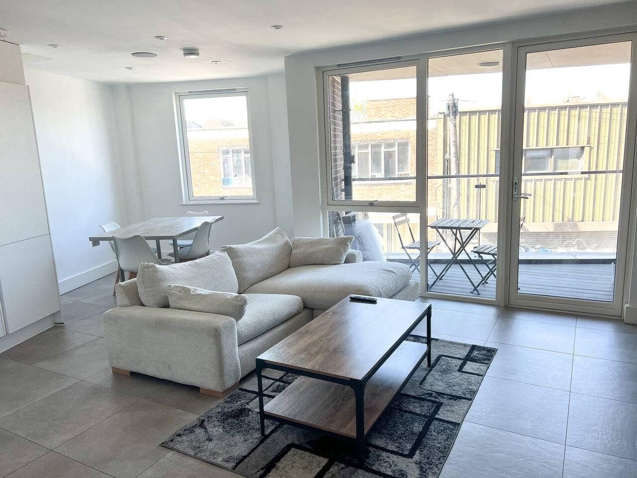 Een moderne woonkamer met een bank, salontafel en een eettafel.