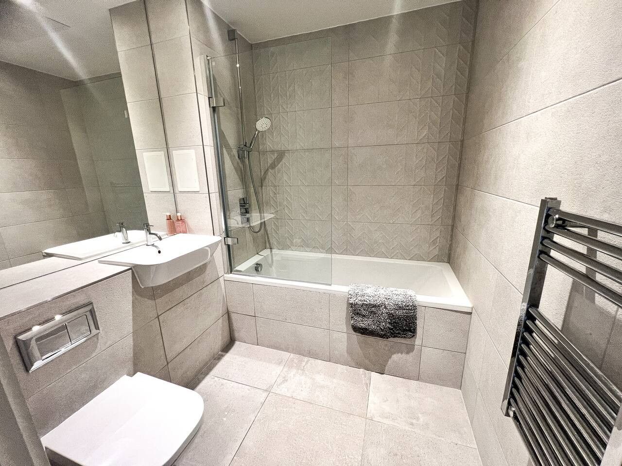 Une salle de bain moderne avec une douche à parois de verre, un lavabo blanc et une baignoire.