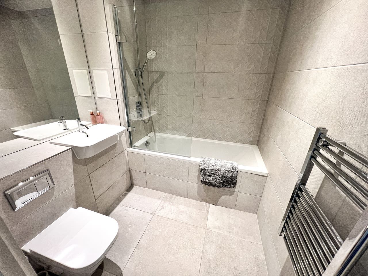 Une salle de bain moderne dotée d’une douche à parois de verre, d’une baignoire, de toilettes et d’un lavabo.