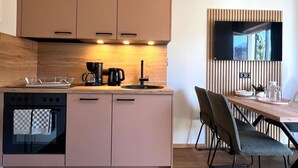 Une cuisine moderne avec des meubles en bois, un four encastré et un coin repas comprenant une table et des chaises.