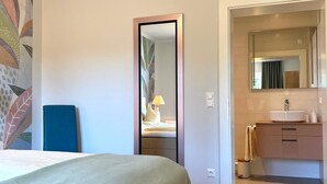 Une chambre d’hôtel comprenant un lit, un bureau, un miroir, une salle de bain avec un lavabo et une douche.
