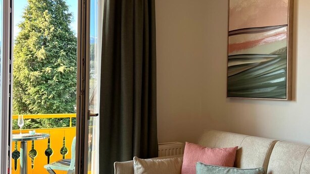 Un salon avec un canapé, un tableau et une vue sur un balcon agrémenté d’une table et de chaises.