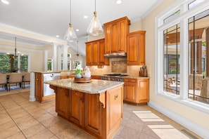A spacious kitchen with wooden cabinets, granite countertops, and pendant lighting.
