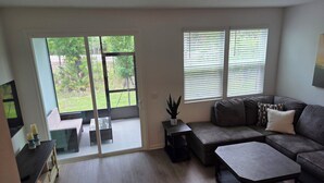 A living room with a sofa, coffee table, and a sliding glass door leading to a balcony. - New St. Augustine Getaway Near Beaches, Golf & Downtown Adventures (St. Augustine)