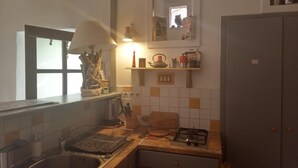 Eine Küche mit Spüle, Herd und Regalen voller Küchenutensilien.