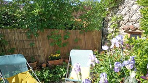 Ein Garten mit Holzzaun, Blumentöpfen und zwei Stühlen.