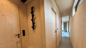 A wooden hallway with a coat rack, a bench, and a door with a keyhole.