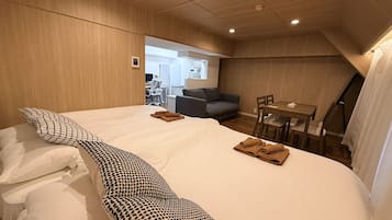 A hotel room with a large bed, a desk, a chair, and a sofa.