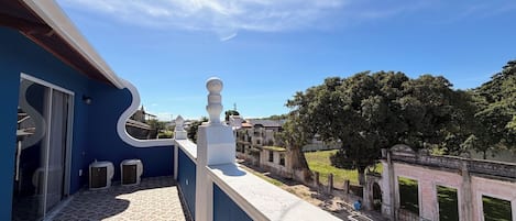 A rooftop terrace with a patterned floor, a white balustrade, and a view of a historic building complex.