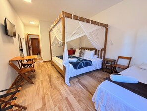 A room with a four-poster bed, a desk, and a chair.