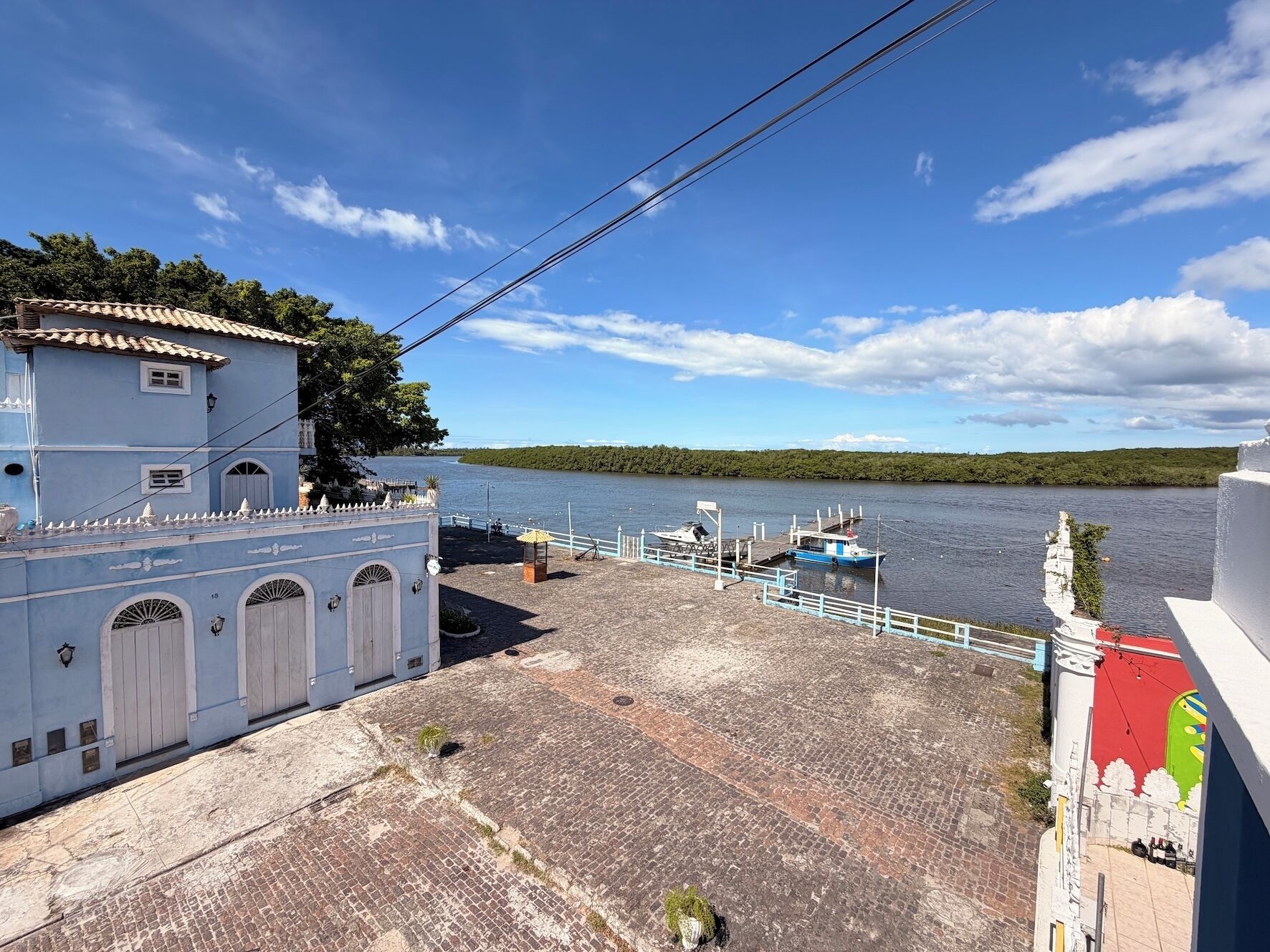 A waterfront property with a paved area, a dock with boats, and a building with arched windows.