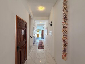 A hallway with a wooden door, a patterned rug, and a wall decorated with seashells. - Imperialis Boutique Hotel (Canavieiras)